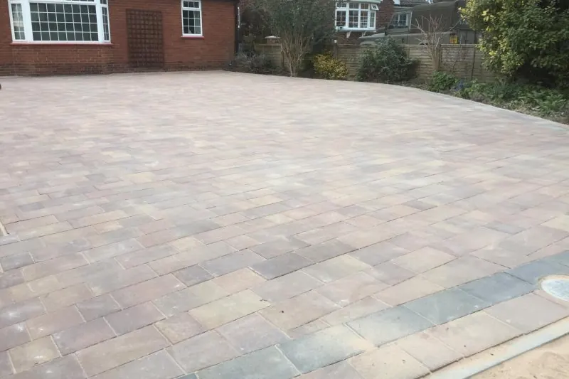 Wide new drive in Marshalls block paving with a charcoal border in front of a brick bungalow